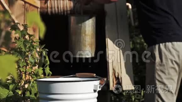 一个人在夏天把水从井里倒进水桶里的慢镜头