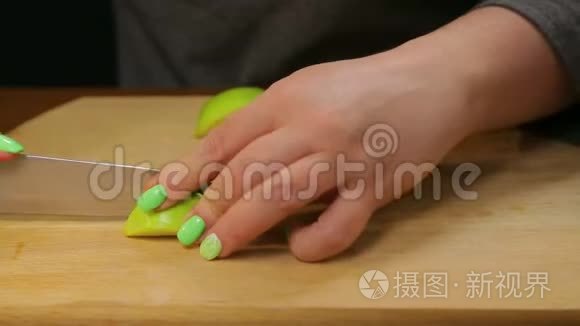 一个女人用刀子把一个绿色的苹果切成小块