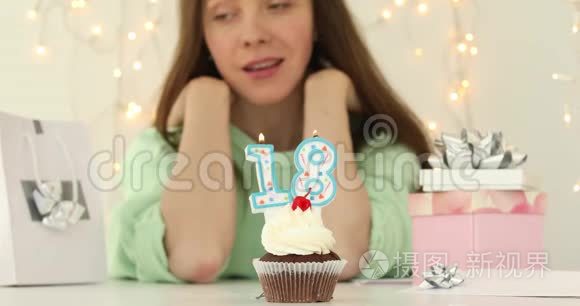 美丽的白种人女孩在蛋糕上吹着18支蜡烛