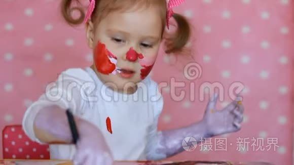 小女孩用油漆画他的脸和手。 肮脏的婴儿艺术家。