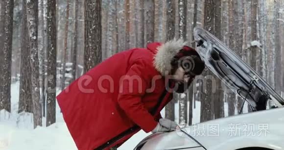 看着汽车发动机的人。 修理破车的人。 冬天开车，麻烦在一条下雪的乡村道路上。