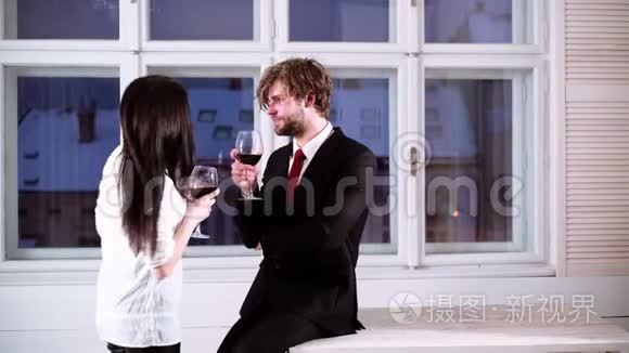 浪漫的夫妇喝红酒。 漂亮的年轻夫妇带着一杯红酒。 年轻浪漫情侣庆祝