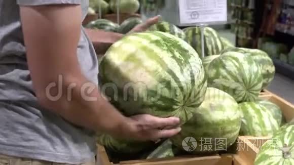 主题养生与天然美食.. 一个高加索人的特写他的手握着，在超市的盒子里挑选一个西瓜。