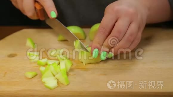 一个女人用一把刀把一个绿色的苹果切成小块。