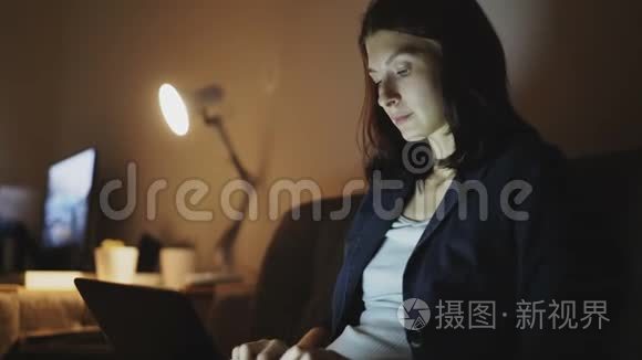 年轻开朗的女人晚上在办公室工作，用手提电脑和打字