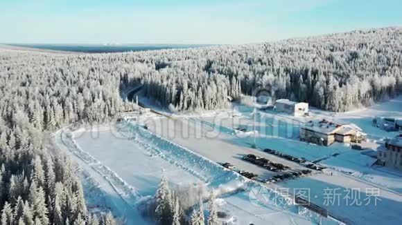 鸟瞰现代滑雪基地，酒店和停车场周围的森林在冬天蓝天。 录像。 从这里看