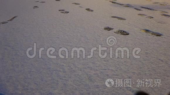 一个穿靴子的女人站在雪地上留下脚印