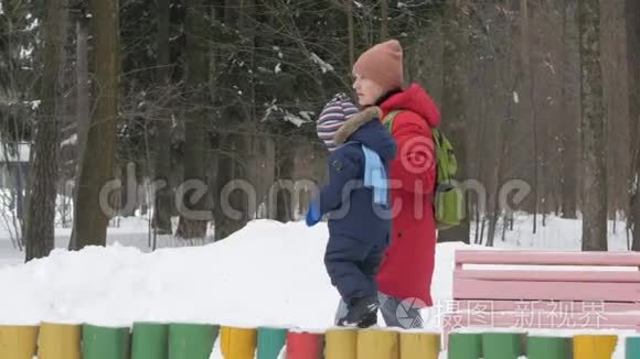 可爱的小男孩和年轻的母亲在冬天和公园里的雪玩耍。 蓝色的孩子`夹克和红色的妈妈。