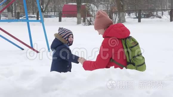 可爱的小男孩和年轻的母亲在冬天和公园里的雪玩耍。 蓝色的孩子`夹克和红色的妈妈。