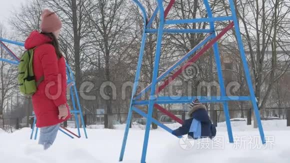 可爱的小男孩和年轻的母亲在冬天和公园里的雪玩耍。 蓝色的孩子`夹克和红色的妈妈。