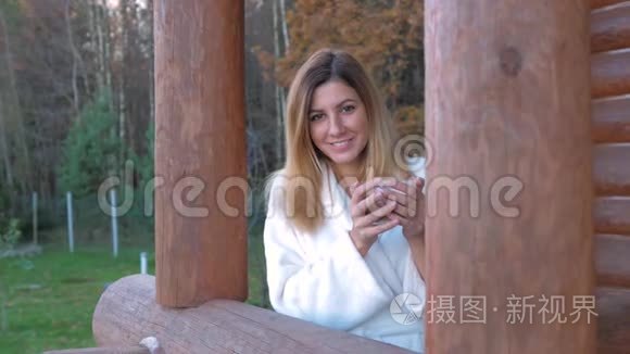 在圆木屋的阳台上喝咖啡的女人视频