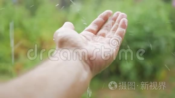 雨滴落在手中的雄性。 在雨中特写的手，你看到水滴在他的手上跳动。 概念