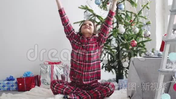 快乐的年轻漂亮女人在装饰好的工作室里的圣诞树附近扔纸屑。 慢动作。 3840x2160