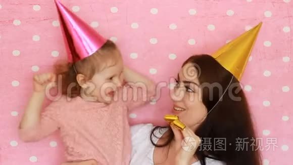 生日快乐。 戴着节日帽子的女人和孩子吹角，笑着笑着。 妈妈和女儿玩得开心