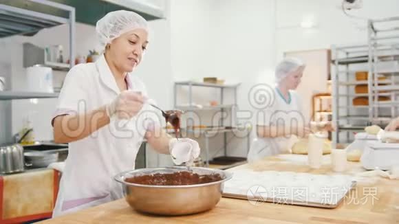 女面包师把巧克力奶油混合在金属碗里做蛋糕