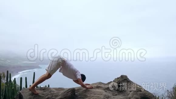 这个人站在悬崖边上，摆出一副看海洋的狗的姿势，在一次海空中呼吸