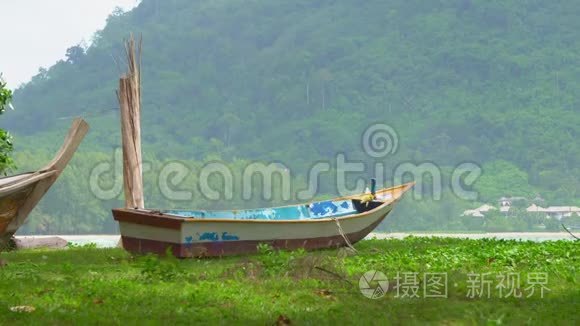 热带岛屿岸边的木船。 海浪。 在海滩上树阴下的小船