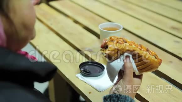 垃圾食品。 丰满的女人吃脂肪热狗和喝热茶。 超重