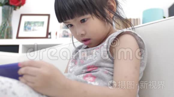 小亚洲女孩在家里微笑着看着手机。