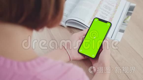 一个年轻女子手中的现代智能手机，绿色屏幕