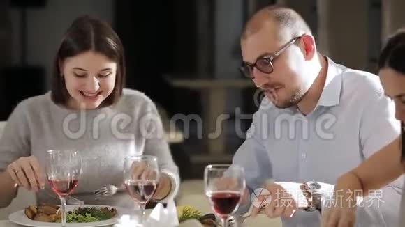 一群朋友在餐馆吃午饭。 一个男人和两个女人在餐馆吃午饭，喝葡萄酒。