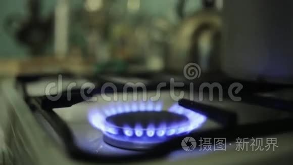 把巨大的铝锅放在燃烧的煤气炉上。 蓝色火焰