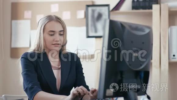 呼叫中心员工在办公室工作。 女孩打电话，在键盘上打字，看着