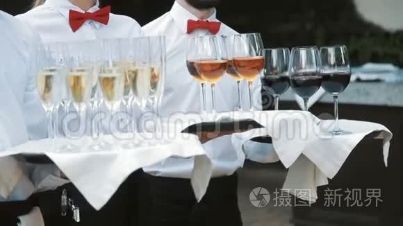 服务员用酒精饮料迎接客人。 托盘上有香槟红酒白酒