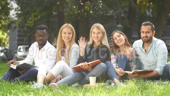混合种族的学生一起坐在大学校园的绿色草坪上