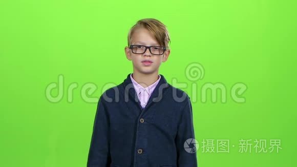 带着眼镜的小男孩看着信用卡，在绿色的屏幕上表现出厌恶。 慢动作