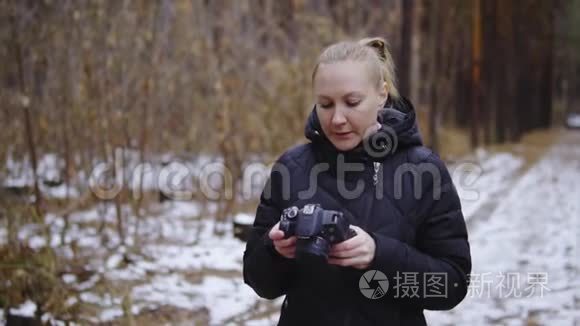 电影拍摄，慢动作.. 女孩摄影师穿过秋天的森林，拍摄大自然的照片。 持有