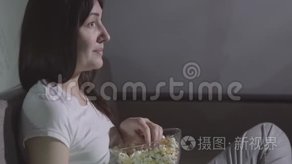 晚上，一个年轻的女人独自用爆米花看电影