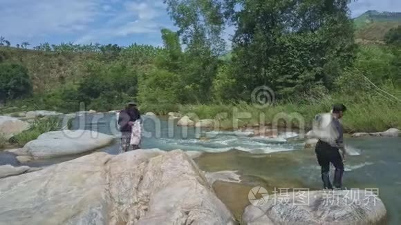 无人视野的人站在岩石上，让人穿越河流