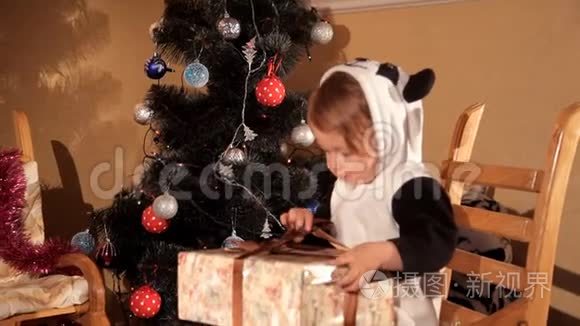 小孩在圣诞树旁打开新年`礼物