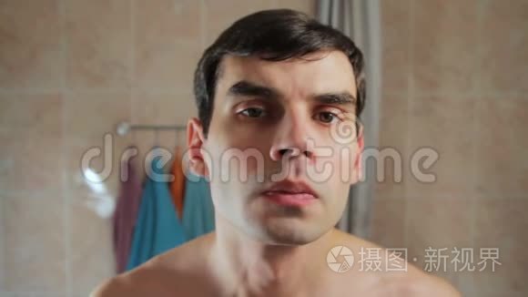男人检查刮胡子的质量。 照镜子检查他的脸。