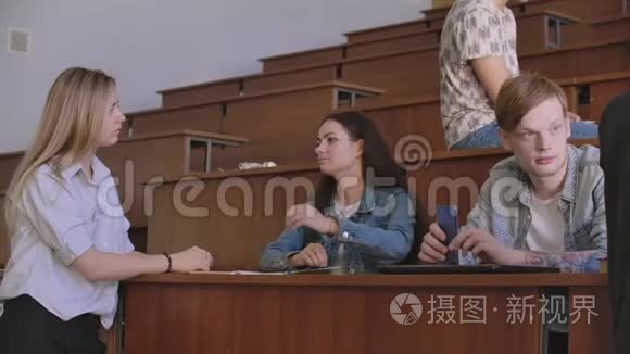 一群开朗快乐的学生在课前坐在报告厅里。 一群快乐的学生坐在