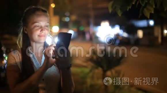 生活方式的女人手里拿着一部手机在夜城与社交网络上的朋友交流。
