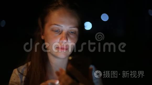 生活方式的女人手里拿着一部手机在夜城与社交网络上的朋友交流。