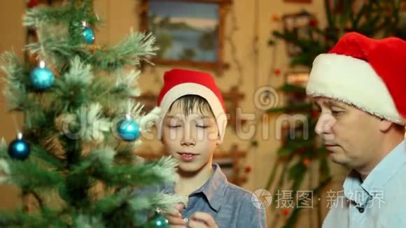 年轻快乐的父子，戴着圣诞老人的帽子，把圣诞树装饰进家门
