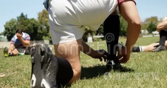 橄榄球队员把鞋带系在场地上视频