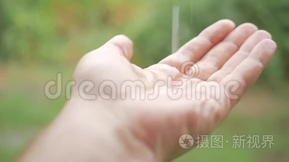 雨滴落在手中的雄性。 在雨中特写的手，你看到水滴在他的手上跳动。 概念