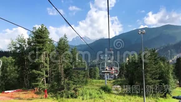 明亮的夏季色彩斑斓的山景，蓝色的多云天空和滑雪电梯与两个女人。 从电梯上看