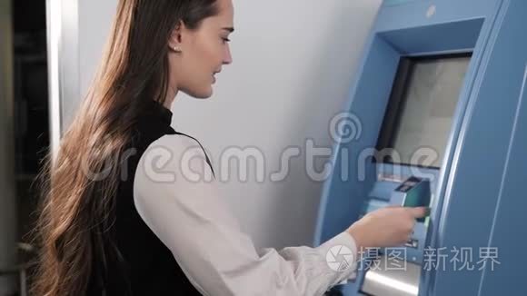 年轻女子在自动取款机上插入一张信用卡，美丽的女孩在购物中心机场候机楼上无触点的NFC银行