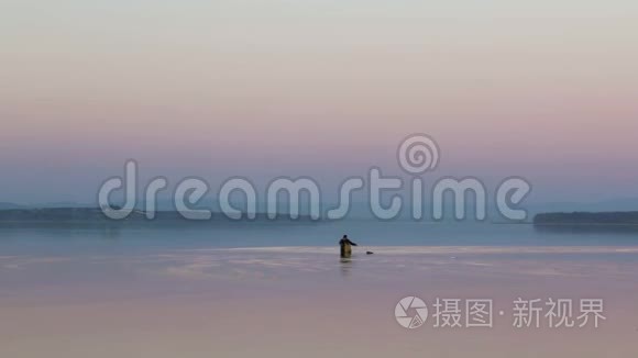 一名渔民在俄罗斯普里莫尔斯基克拉伊的阿穆斯基湾安装渔具，背景是一片红色的日落天空。