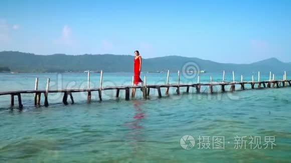 穿着红色长裙走在码头上的美女。 Phu Quoc岛。 那个女人走在皮尔西。 照相机开着灯