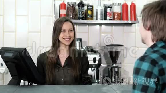 漂亮的女咖啡师从一位顾客那里点餐，顾客在咖啡店里放了一个平板电脑，她微笑着