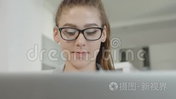 年轻的女学生在家里使用笔记本电脑，在社交网络上聊天，微笑着