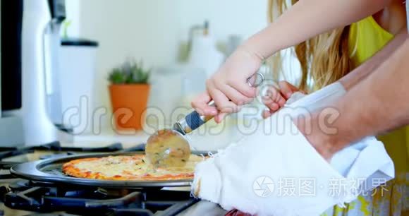父亲和女儿切厨房里的披萨