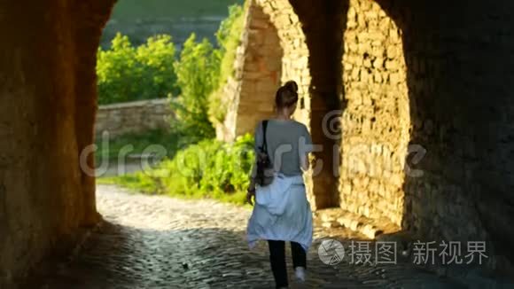 走在秋城街户外的女人。 4K. 年轻的女人在散步时使用智能手机。 傍晚时分