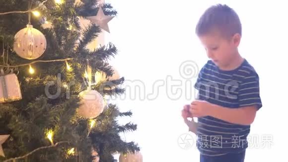 可爱的小男孩用球和灯装饰圣诞树。在家里准备过年的孩子。